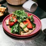 Grilled vegetable plate with red peppers, zucchini, asparagus, and fresh greens served on a purple plate at a Denver restaurant