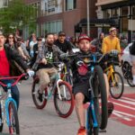 Group of cyclists riding through downtown Denver during a fun community bike event.