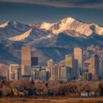 Denver skyline with the majestic Rocky Mountains in the background under a clear sky, showcasing the perfect urban and mountain contrast.