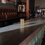 Close-up of hazy IPA on bar amid wooden taps and industrial brewery vibe in RiNo Denver.