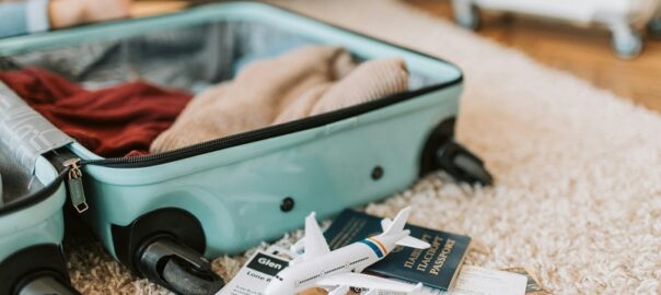 Packed suitcase with passport, toy airplane, and travel essentials for a family trip to Denver.