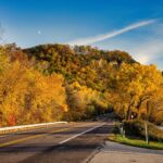 Scenic mountain road near Denver, Colorado, surrounded by colorful trees and autumn foliage during a scenic road trip.